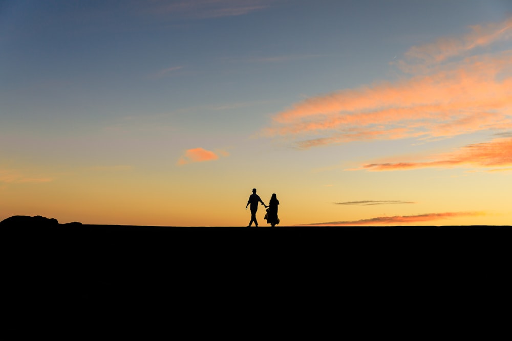 夕暮れ時の丘の上に立つ2人のシルエット