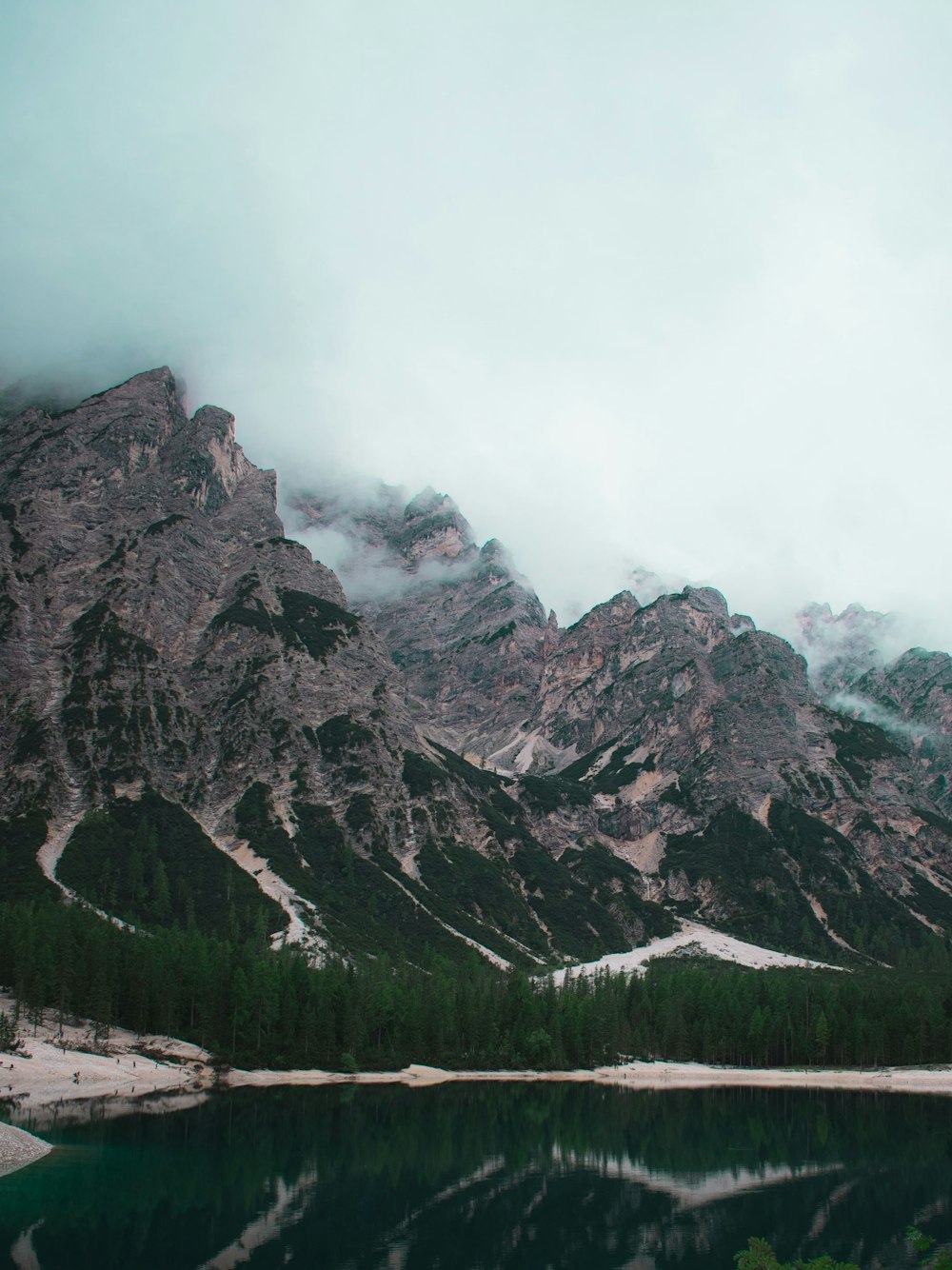 Montaña rocosa gris bajo el cielo blanco durante el día