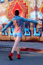 A model wearing baggy jeans and jorts on a city street with graffiti walls.