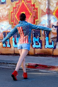 A model wearing baggy jeans and jorts on a city street with graffiti walls.