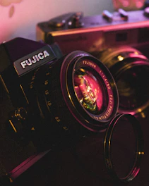 Close-up of a vintage camera lens with soft violet light reflecting off its glass.