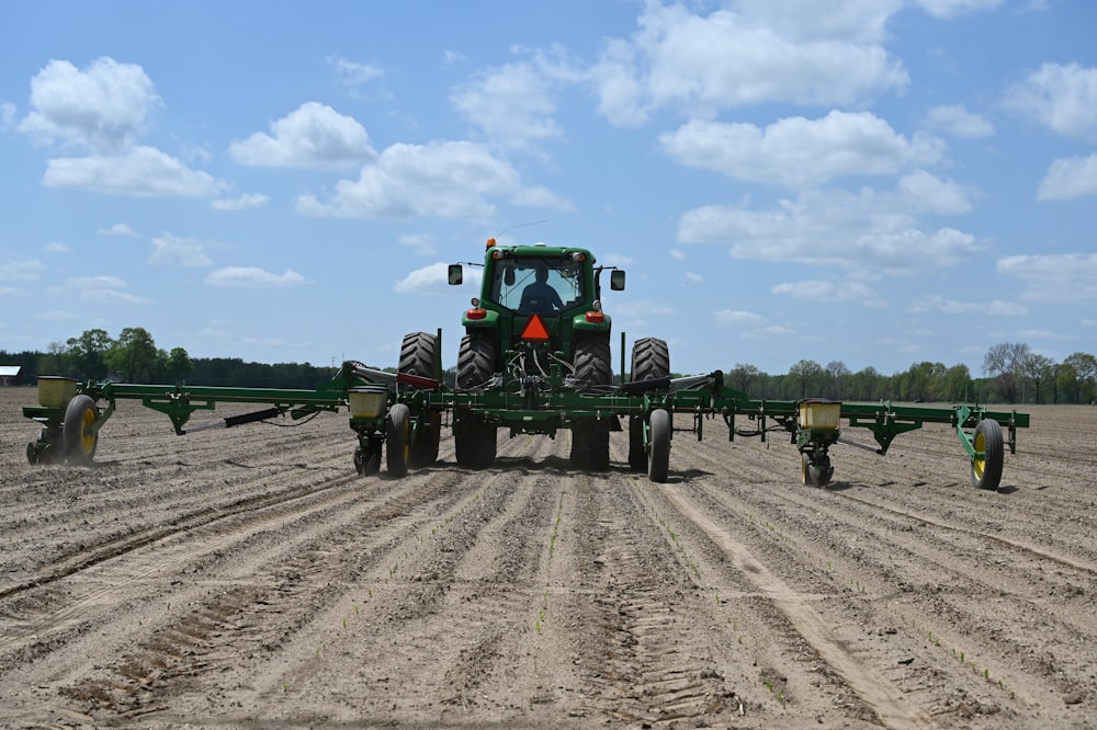 tracteur vert sur un champ brun sous un ciel bleu pendant la journée