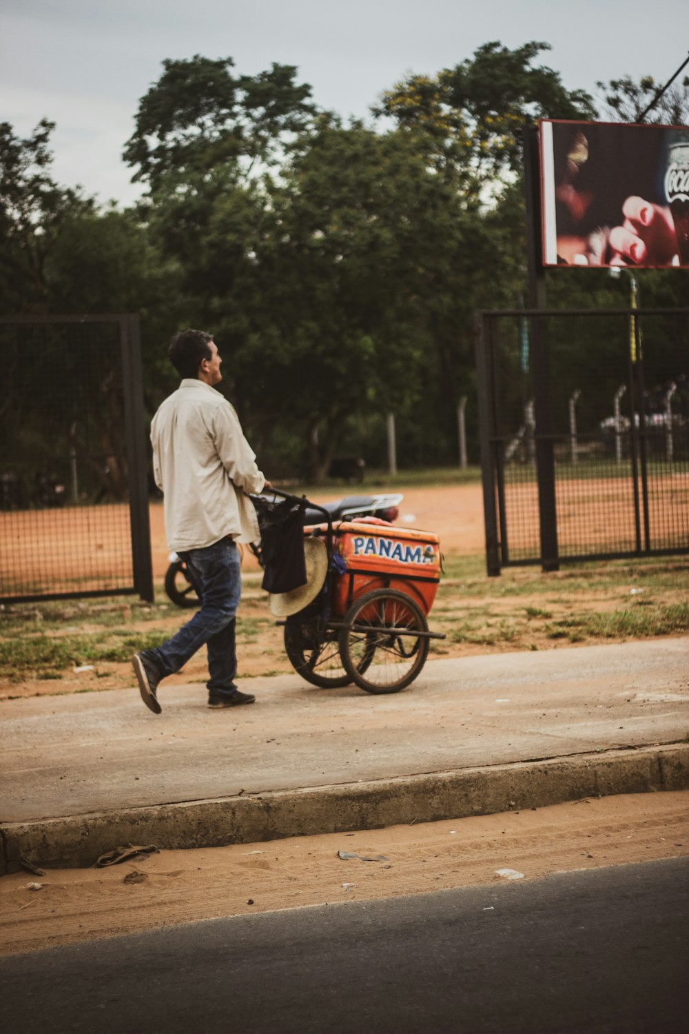 man in white dress shirt and blue denim jeans riding on red and black bicycle during