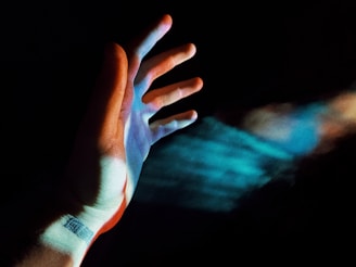 persons left hand with blue and purple light