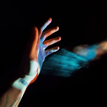 persons left hand with blue and purple light