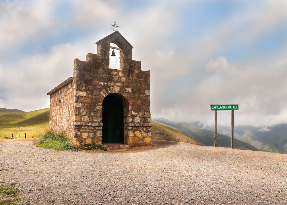 brown concrete building near green mountain under white clouds during daytime