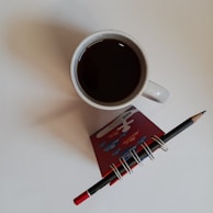 A team member writing a guest article on a notepad beside a cup of coffee.