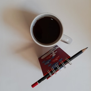 A notepad and pen next to a coffee cup on a desk, symbolizing content creation.