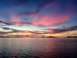 A serene tropical sunset over St. Kitts harbor, blending warm hues with soft, flowing watercolor textures.