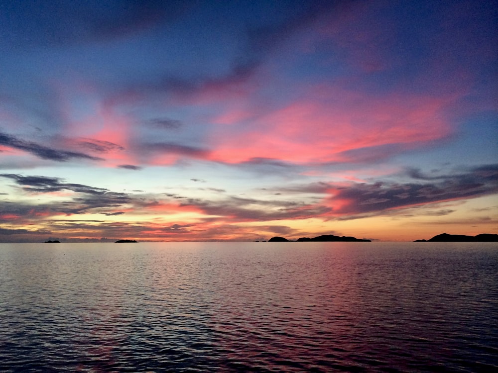 body of water under cloudy sky during sunset