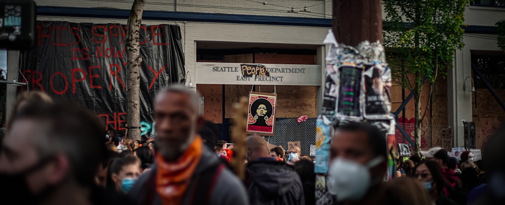 man in black and orange jacket standing near people during daytime