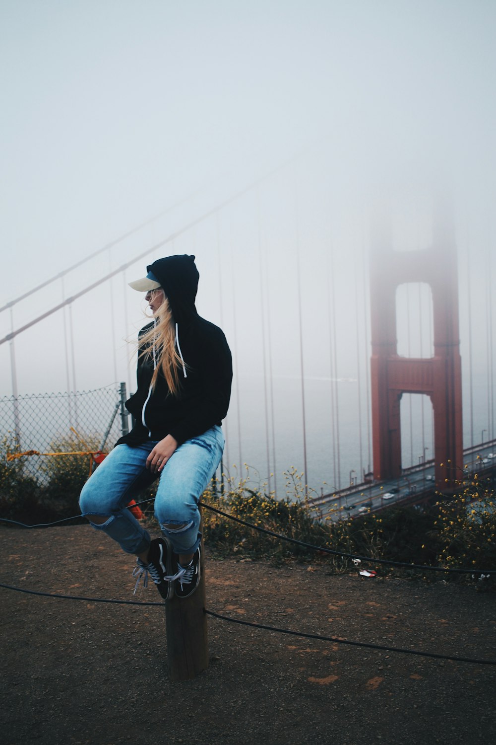 woman in black long sleeve shirt and blue denim jeans standing on pathway