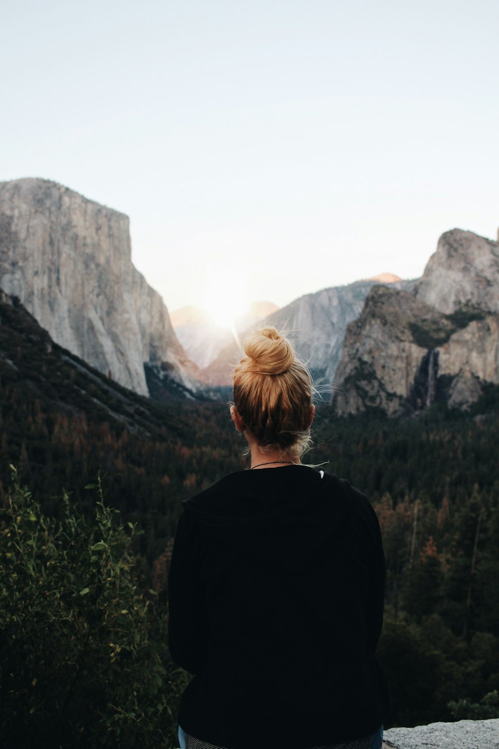 woman in black jacket standing near mountain during daytime