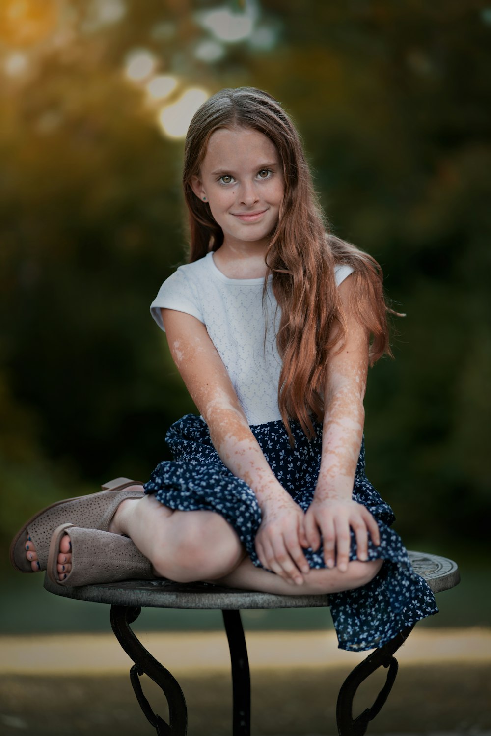 woman in white crew neck t-shirt and black and white floral skirt sitting on ground