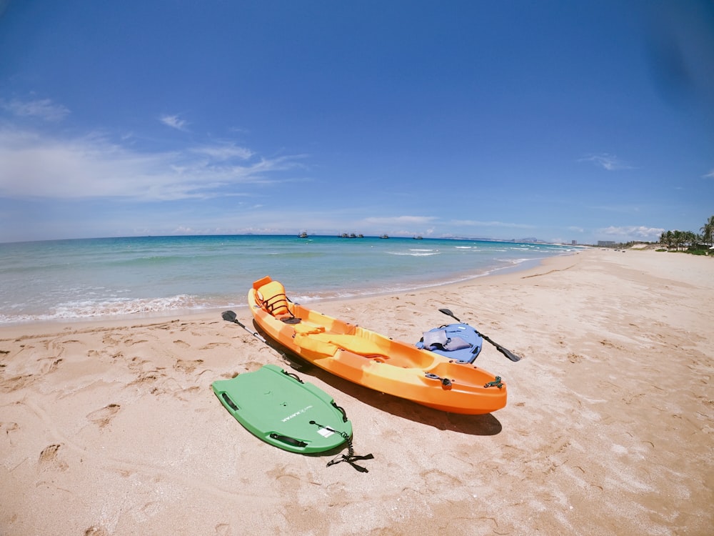 orange and green kayaks on beach shore during daytime