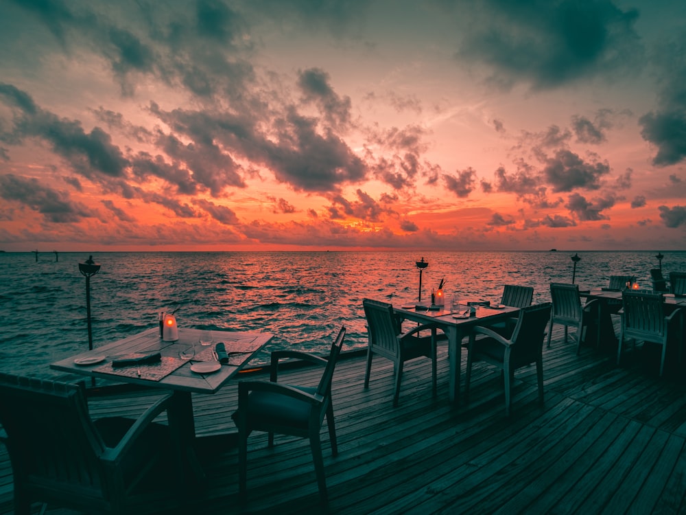 black wooden table and chairs on wooden dock during sunset