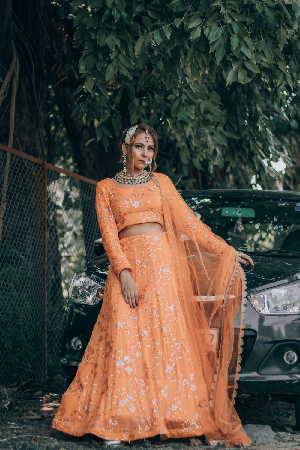 woman in orange dress standing beside black car