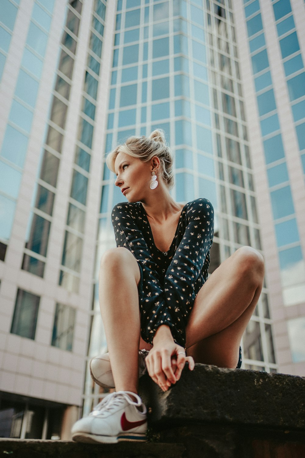 woman in black and white floral sleeveless dress sitting on white concrete bench during daytime