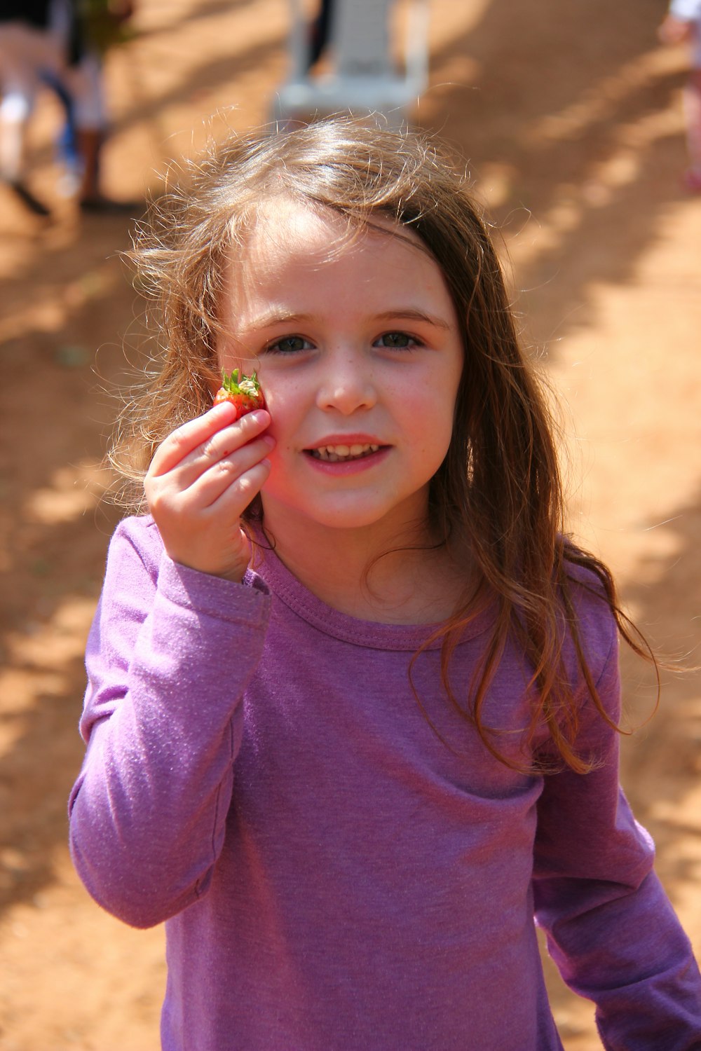 girl in pink long sleeve shirt holding green and yellow lollipop