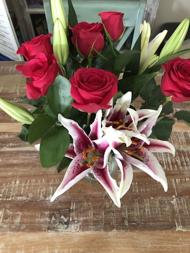 A vibrant bouquet of fresh roses and lilies arranged in a rustic vase, glowing softly under warm mall lighting.