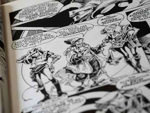 A black and white comic book page features three characters having a conversation. They wear futuristic attire with geometric patterns and accessories. Speech bubbles contain dialogue between the characters, and the background includes stylized designs.