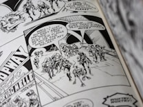 A black and white comic book page featuring a group of armored characters walking together. Speech bubbles contain dialogue, and the background displays some architectural details and signage.
