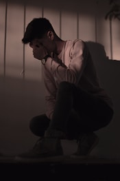 man in white dress shirt sitting on the floor unhappy and thinking about his relationship