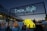 An outdoor festival or event taking place at dusk with a large illuminated sign reading 'Dream Night' displayed above several white tents adorned with string lights. People are gathered around, and a large central sculpture made of stacked yellow blocks, each containing a smaller light or decoration, is prominently featured. The sky is transitioning from day to night, creating a calm atmosphere.