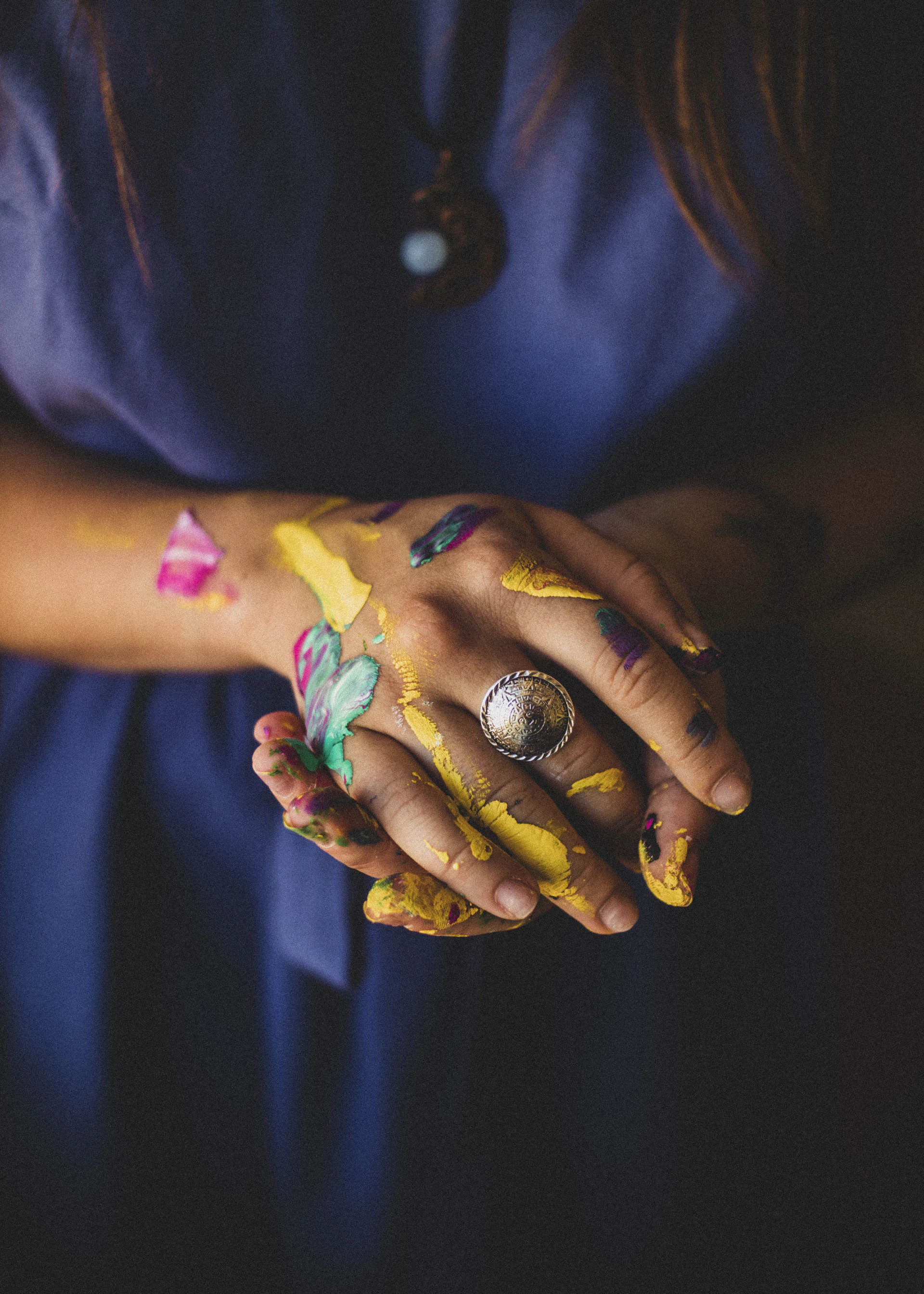 person with purple blue and green paint on hand