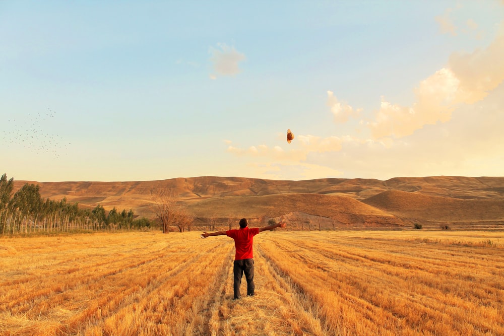 man in red jacket walking on brown grass field during daytime