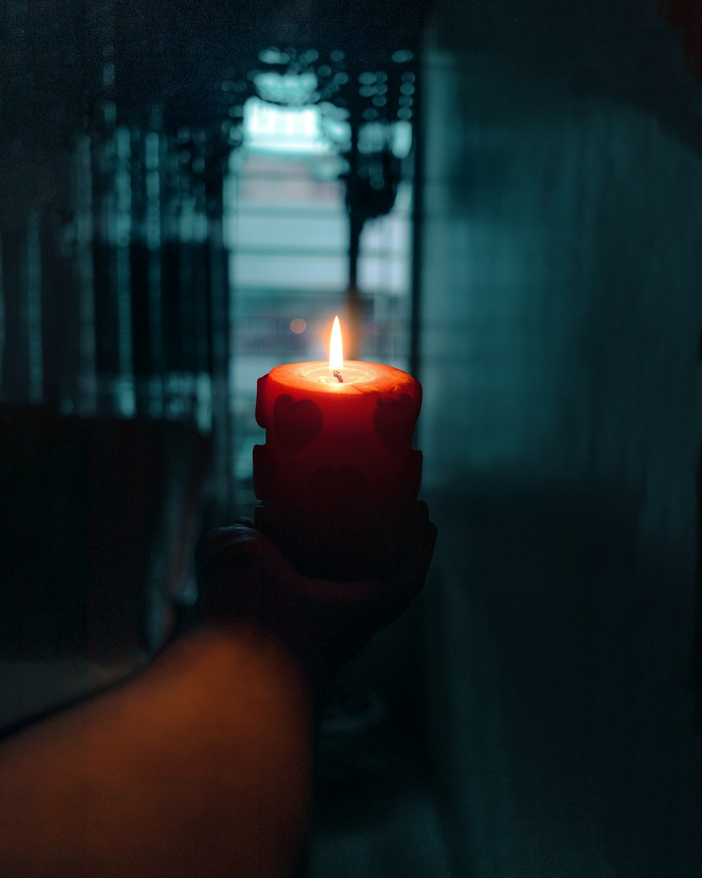 person holding red pillar candle