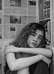 grayscale photo of woman leaning on wall