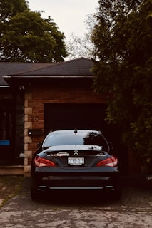 gray bmw car parked beside brown wooden house