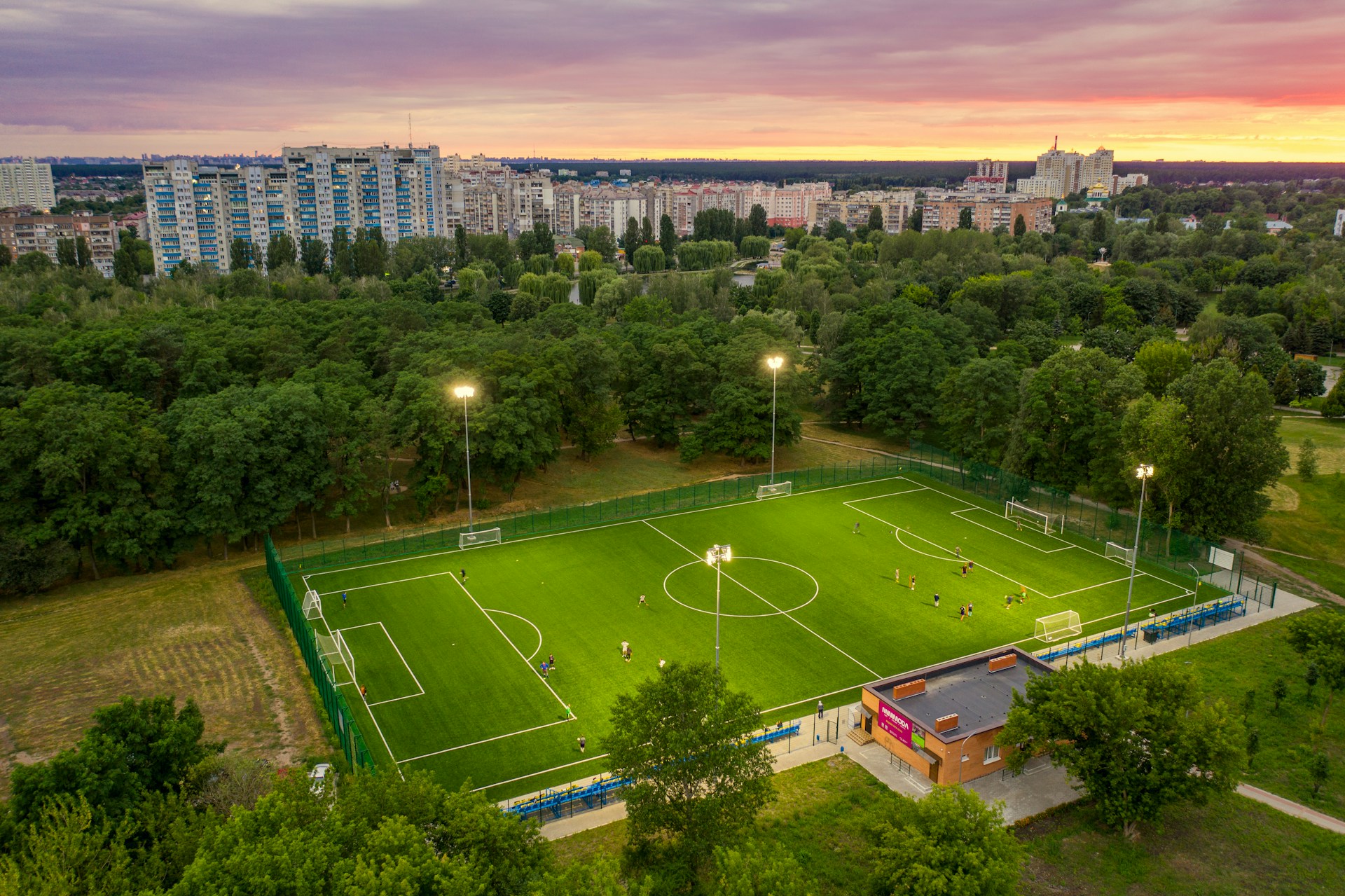 green grass field with trees and buildings in distance