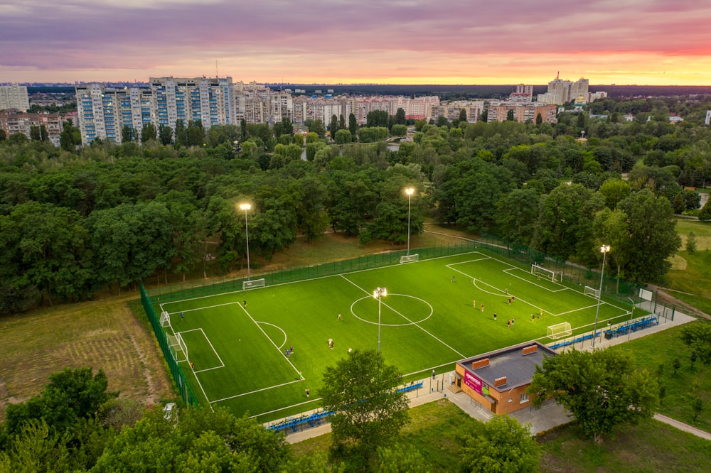 green grass field with trees and buildings in distance