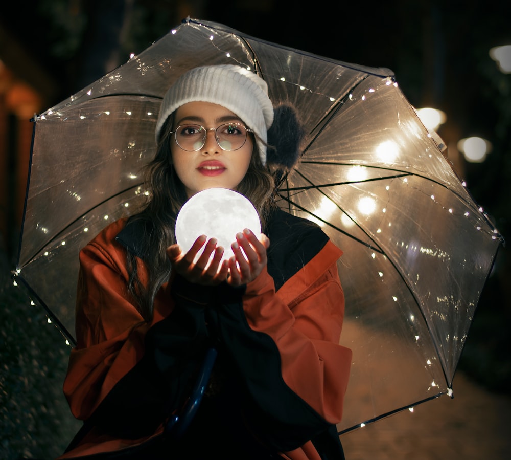 Femme en veste rouge et noire tenant un parapluie