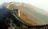 A section of the Great Wall of China stretches across a mountainous landscape, featuring a series of watchtowers connected by a stone pathway. The wall winds through barren trees and the scene is enveloped in a misty atmosphere, creating a sense of depth and history.