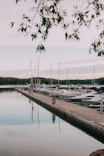 A peaceful marina with small boats docked near a forested shore in Dalsbruk.
