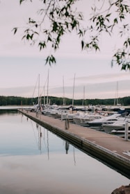 A peaceful marina with small boats docked near a forested shore in Dalsbruk.