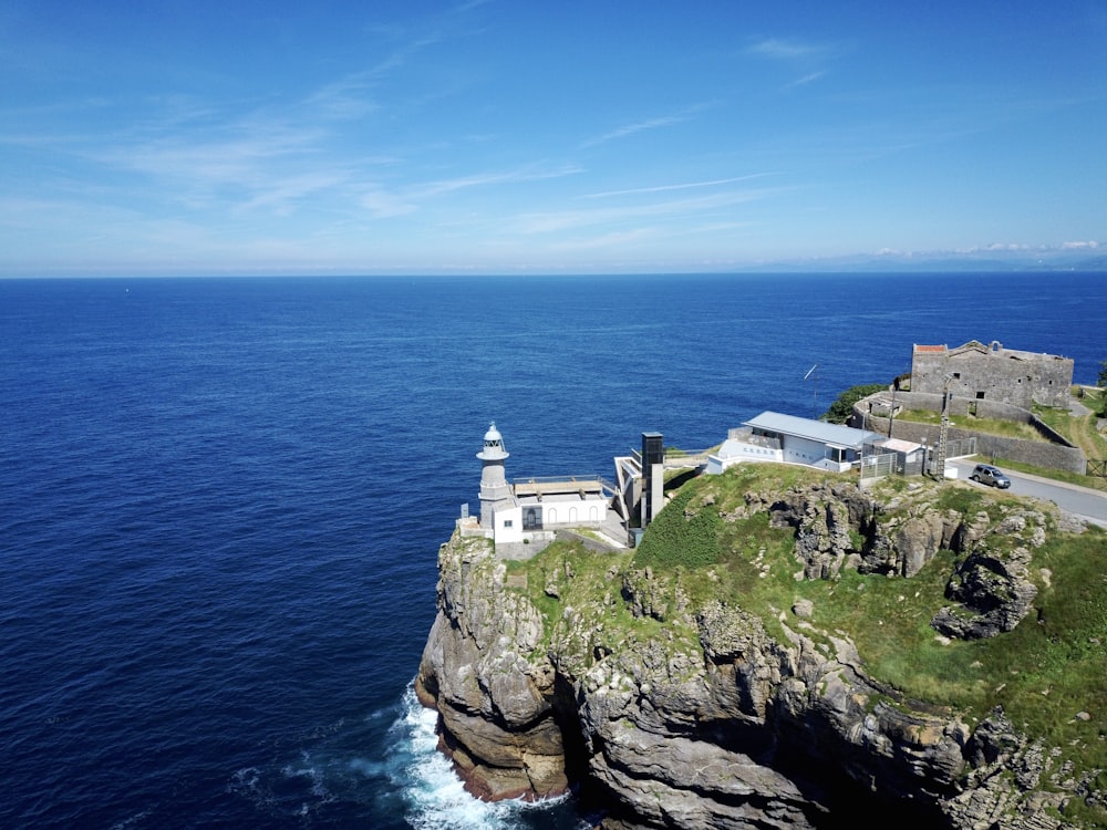 white concrete building on cliff by the sea under blue sky during daytime