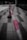 A close-up view of a red and white striped barrier tape stretched across a tiled floor, with the focus primarily on the tape. In the background, a blurred traffic cone is visible.