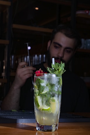 A vibrant cocktail with tequila garnished with fresh lime and herbs on a wooden table.