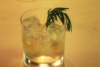 A stylish cocktail glass garnished with fresh herbs, glowing softly in the evening light.