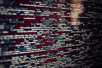 Several lines of source code are displayed on a screen. The code includes text in different colors which likely categorize different types of information such as variables, functions, and comments.