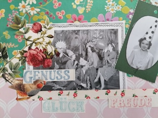 A collage featuring a black-and-white photograph of people in party hats, blowing up balloons and appearing to celebrate. The image is decorated with vintage floral patterns, roses, and cutouts of birds. Text is also included, with words like 'GENUSS', 'GLÜCK', and 'FREUDE' in pastel colors.