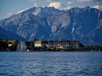 white and brown building near body of water and mountain