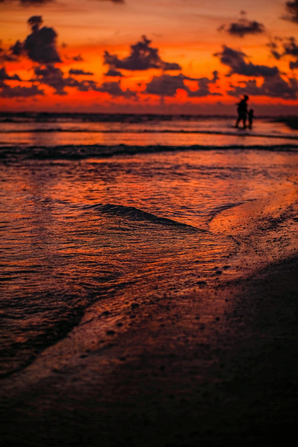 Silueta de persona caminando en la playa durante la puesta del sol