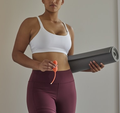 woman in white sports bra and purple leggings holding black speaker