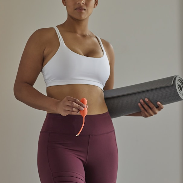 woman in white sports bra and purple leggings holding black speaker