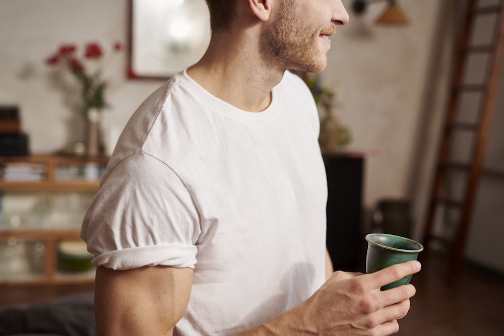 man in white crew neck t-shirt holding green ceramic mug